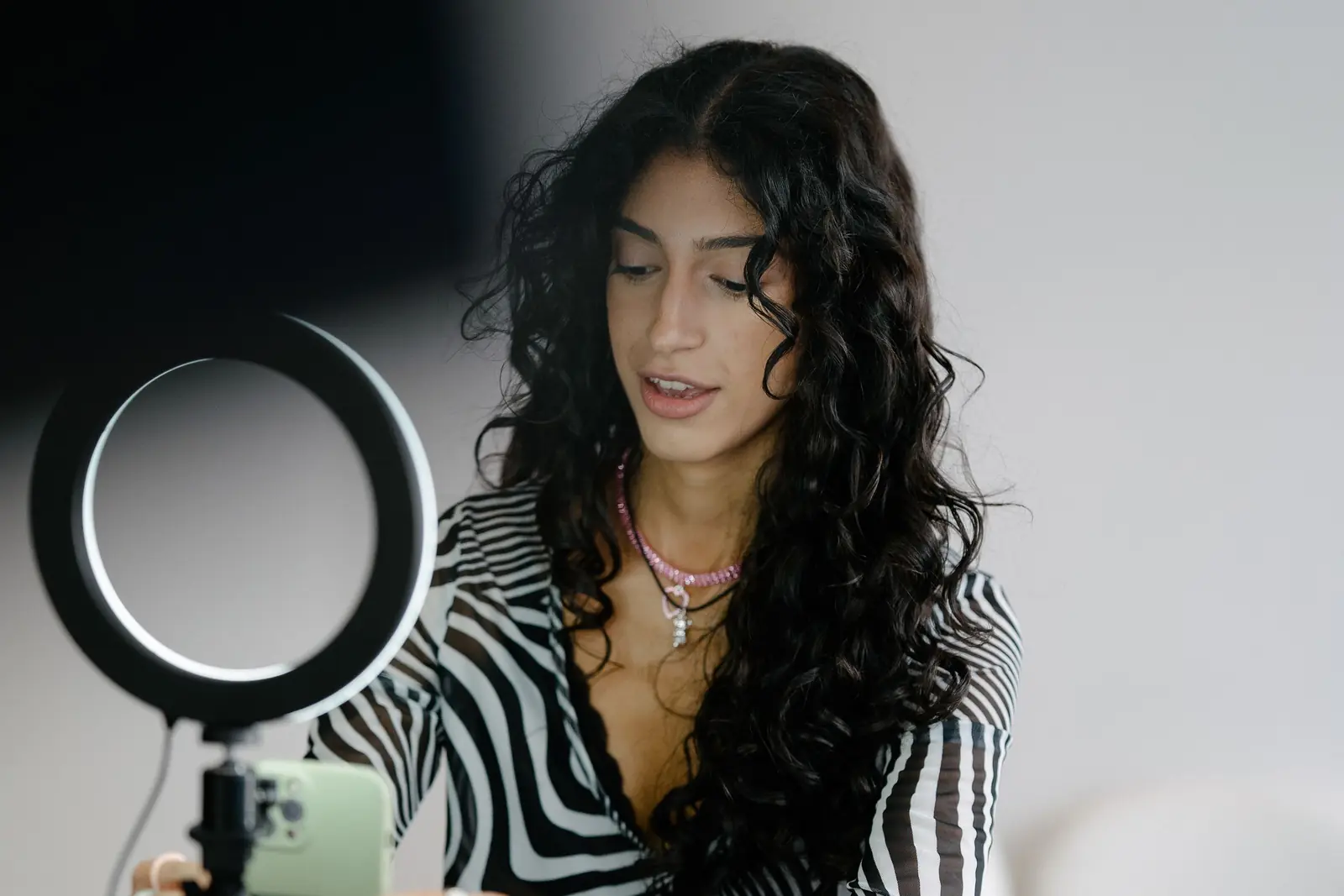 A creator setting up her phone in a ring light to film